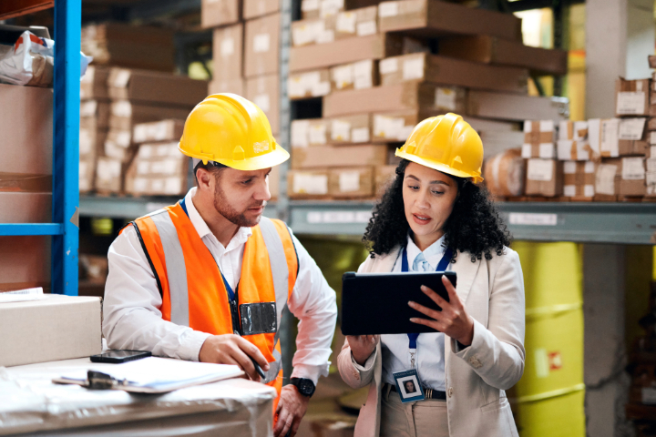 Two workers using a tablet in a warehouse