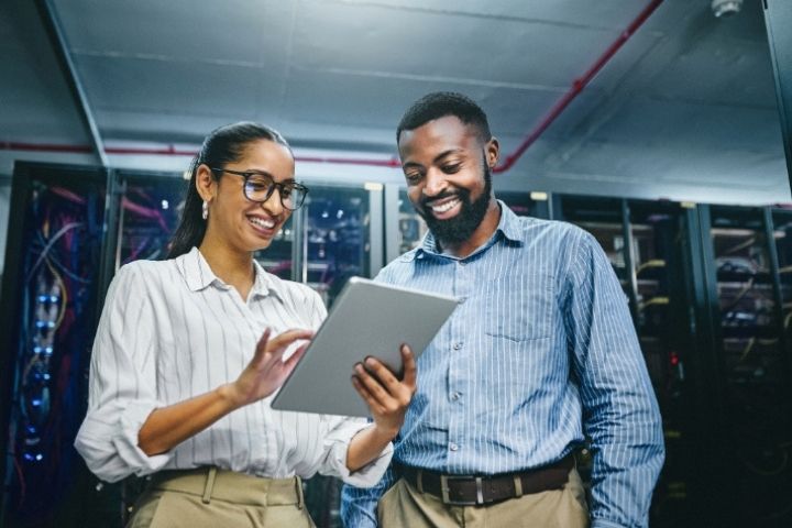Two employees in a computer bank room using a tablet
