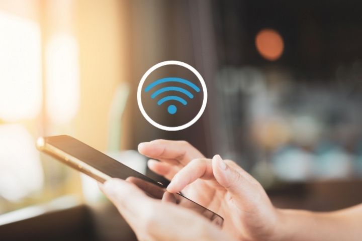 Someone holding a mobile device with a Wi-Fi icon